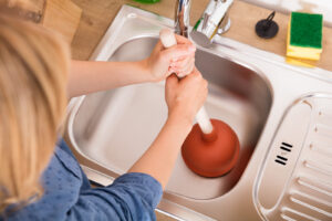 Using a plunger on a blocked kitchen sink in a Melbourne home